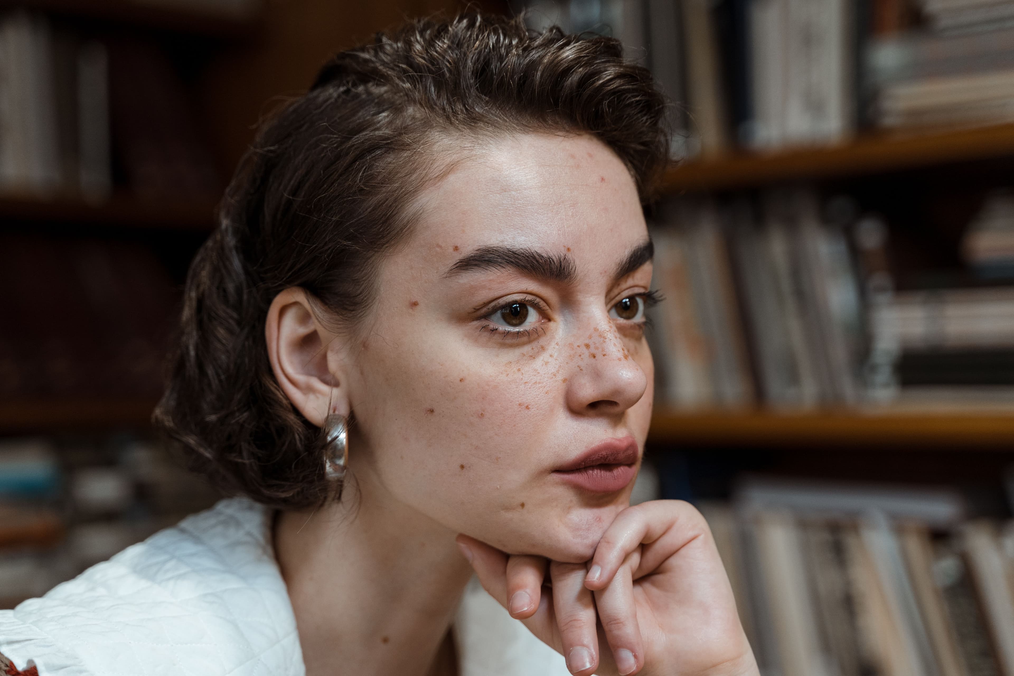 Close-up of a woman with an even skin tone applying brightening serum to manage hyperpigmentation