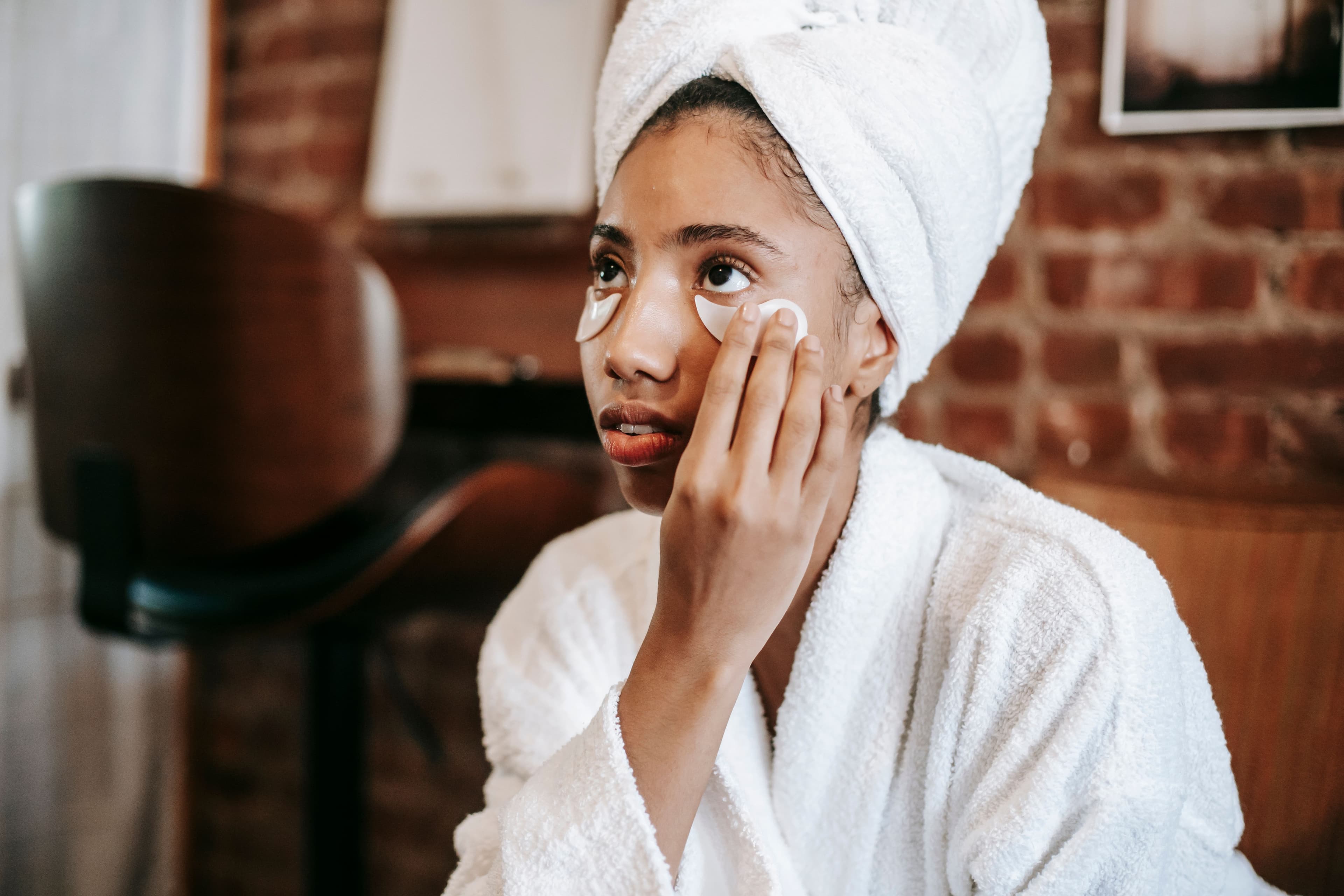 Woman examining a dry, flaky patch of skin on her cheek in natural light