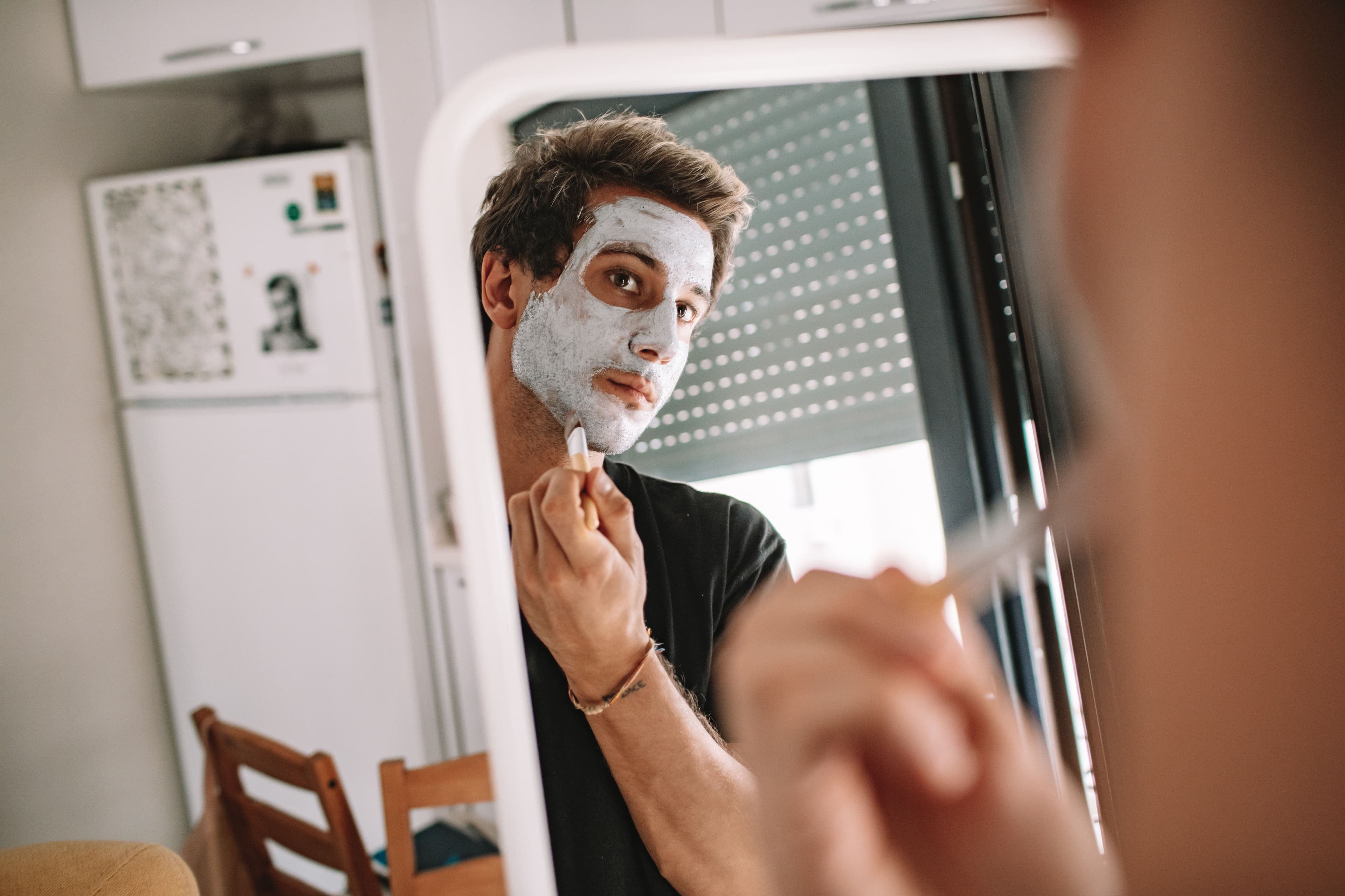 Simple men's skincare and grooming essentials including cleanser and beard oil on a dark surface